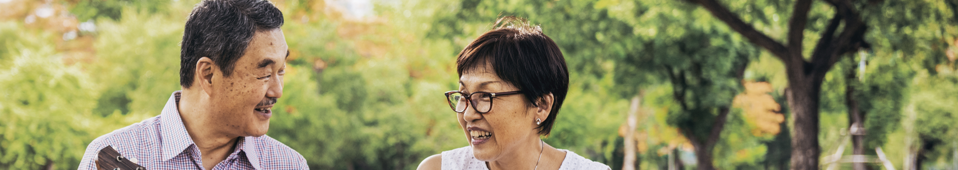 two asian people smiling at each other in a park
