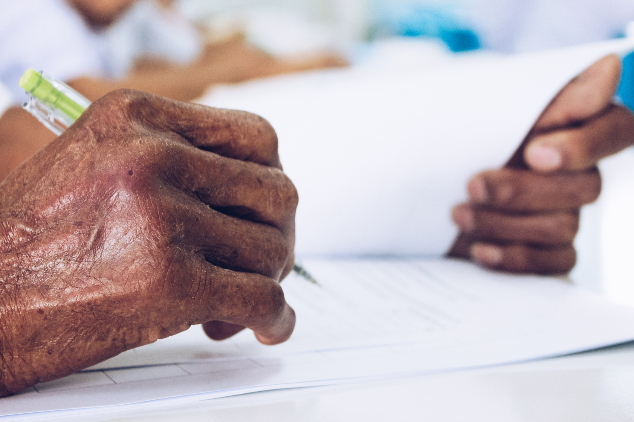 elderly individual's hands handling a pencil and paper documents