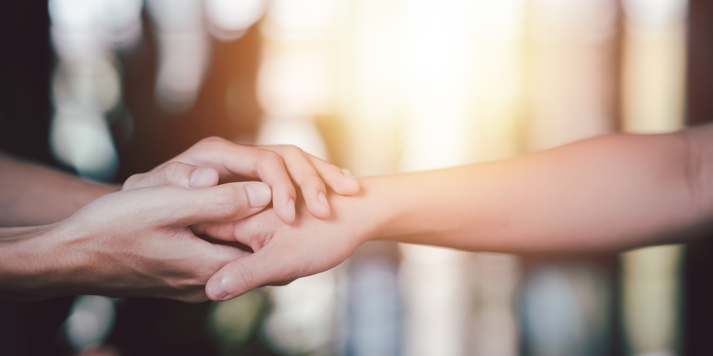 a person holding another person's hand with both of their hands in a supportive manner