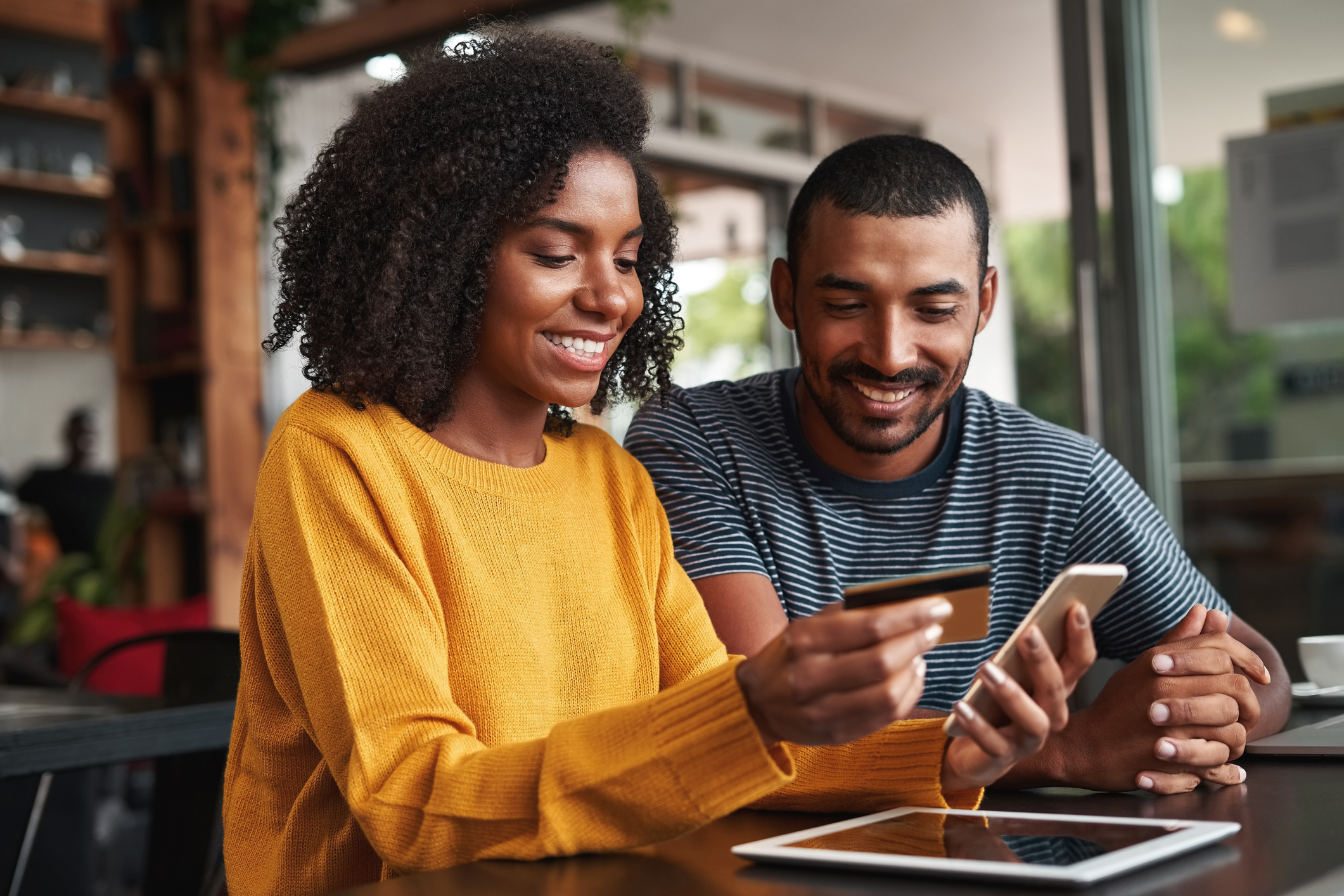 Man looking at his girlfriend using a debit card