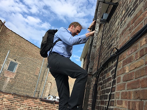 Videographer climbs a building in Chicago to get a shot for this documentary project.